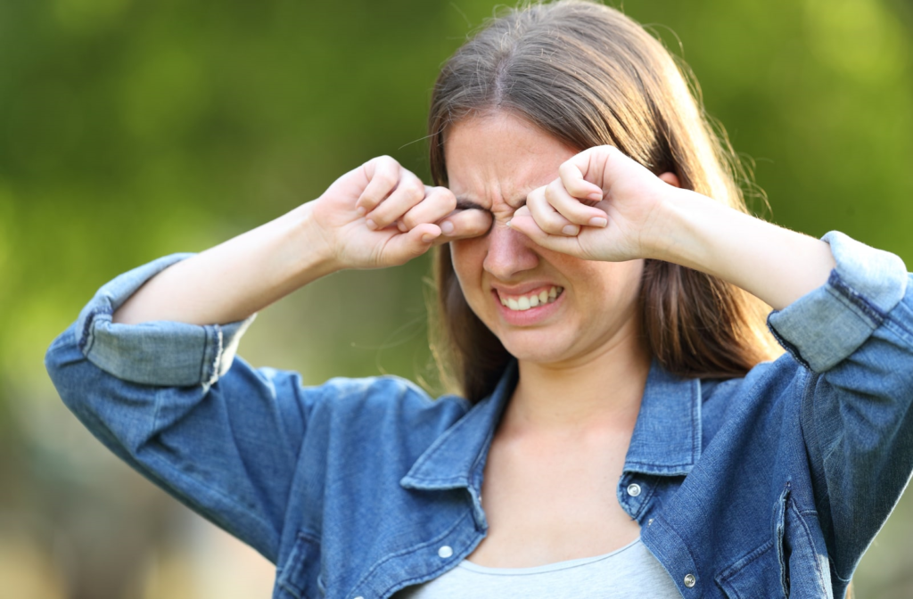 Woman suffering from dry eyelids grimacing and rubbing her irritated eyes