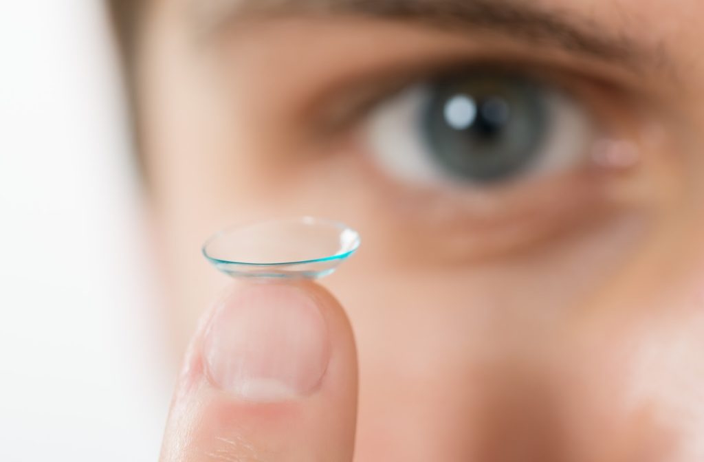 A teenage boy resting his contact lens on the tip of his finger