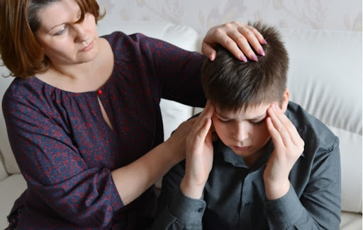 A mother caring for her son who has a headache in need of vision therapy