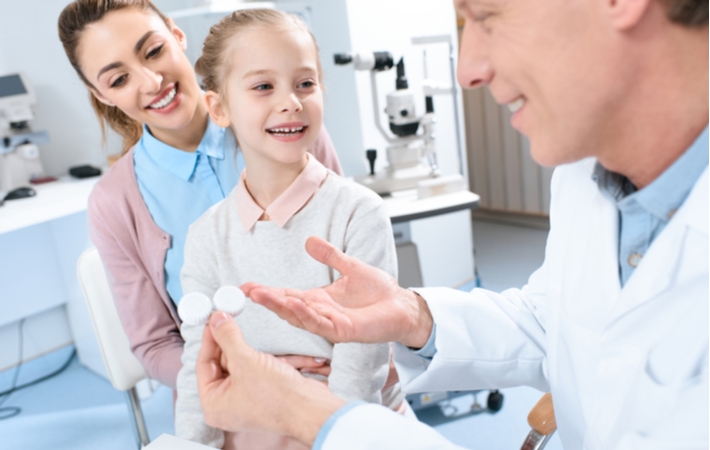 A little girl and her mother at the optometrist getting a contact lens exam and fitting