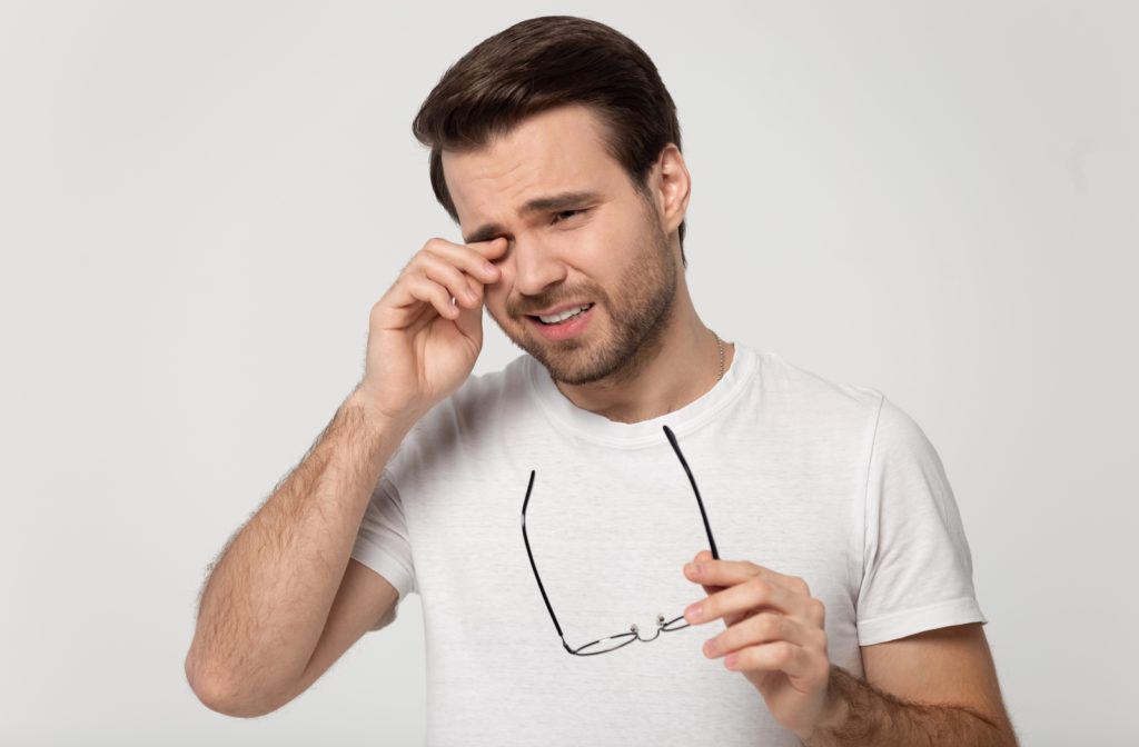 Man rubbing his eye in discomfort because he suffers from dry eye