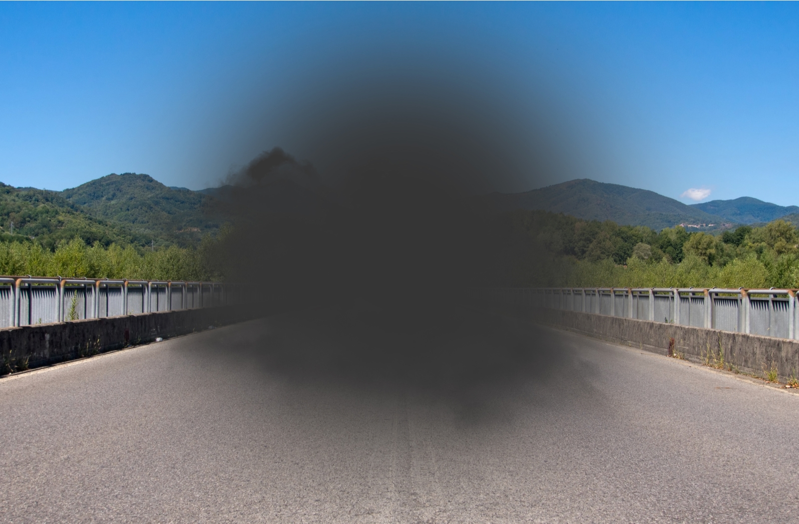 A view through the eyes of someone with macular degeneration, looking down a roadway with a large, dark, visionless spot in the middle