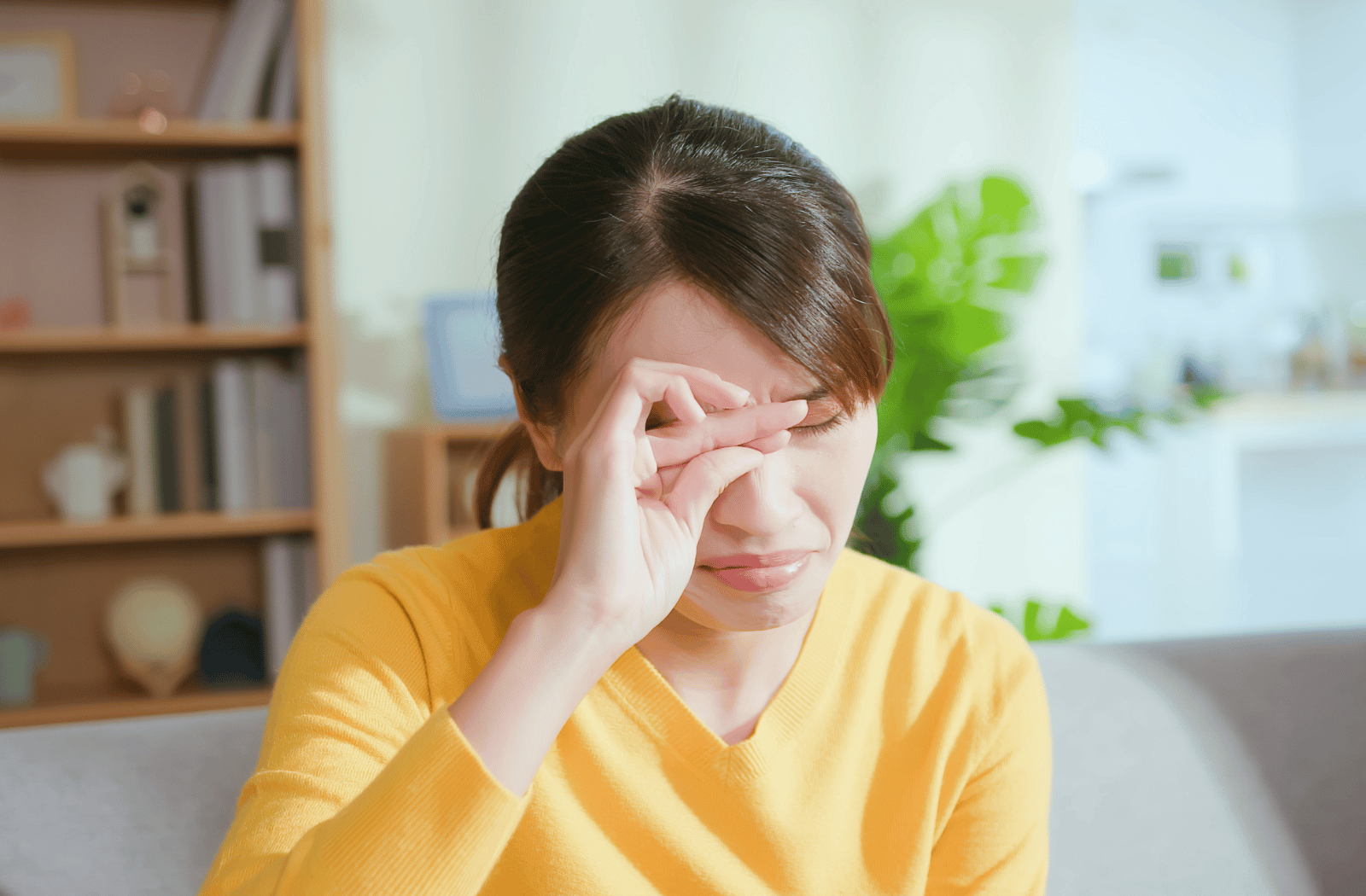 A woman closes and rubs her eyes due to dry eye pain
