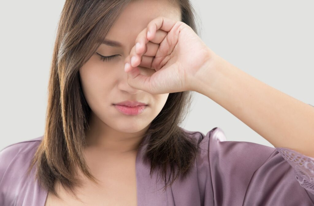 A woman rubbing her eyes after waking up from sleeping all night.