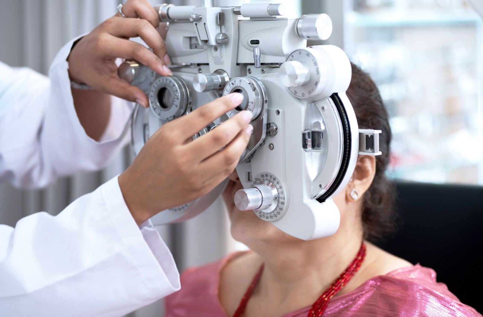 An optometrist adjusts a phoropter to check their patient's prescription.