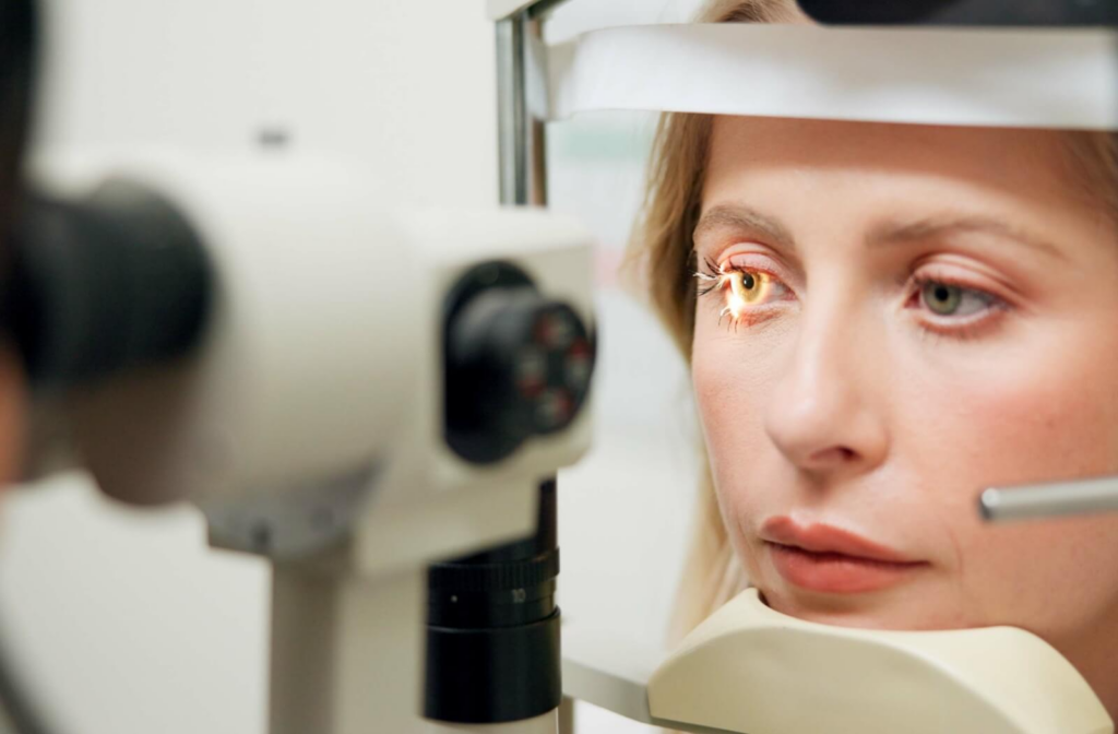 Person undergoing an eye exam using a slit lamp, with focused light illuminating the surface of her eye for detailed assessment by an optometrist.