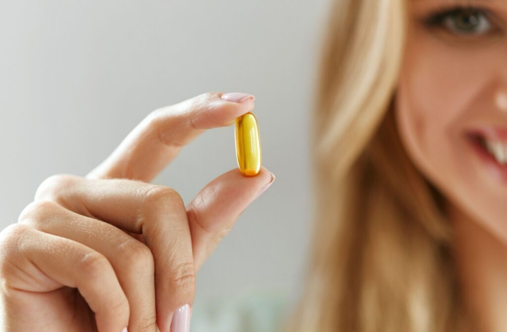 Close up of an adult holding an omega-3 supplement